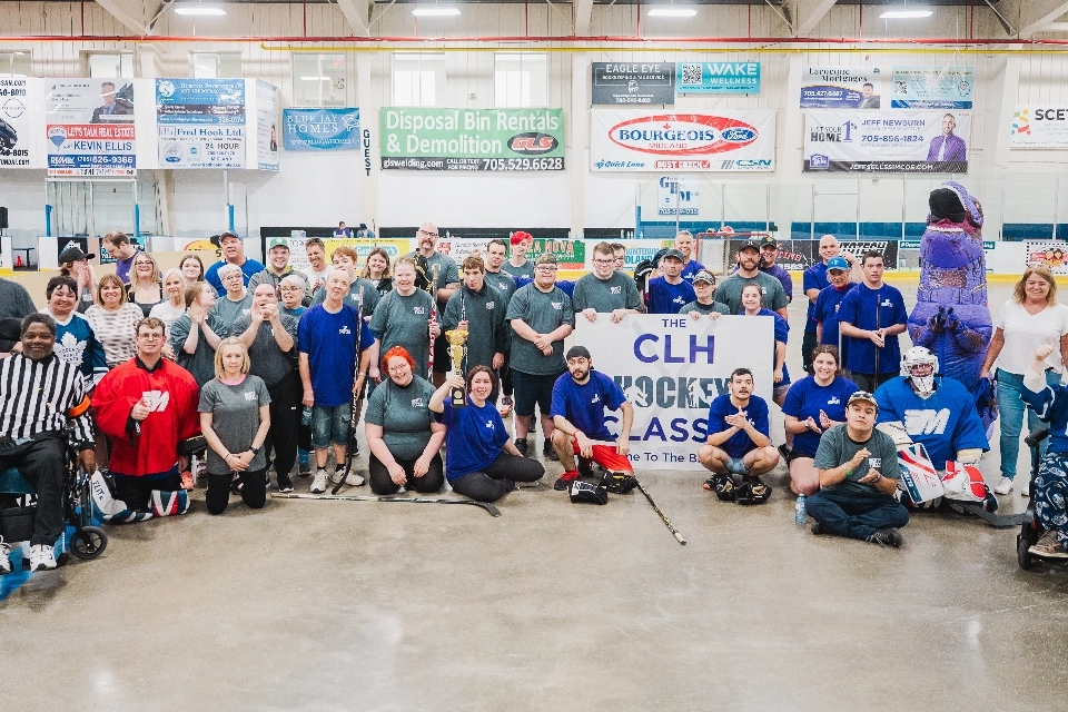 A large group of hockey players, referees and coaches of all ages pose for a picture in the Midland arena