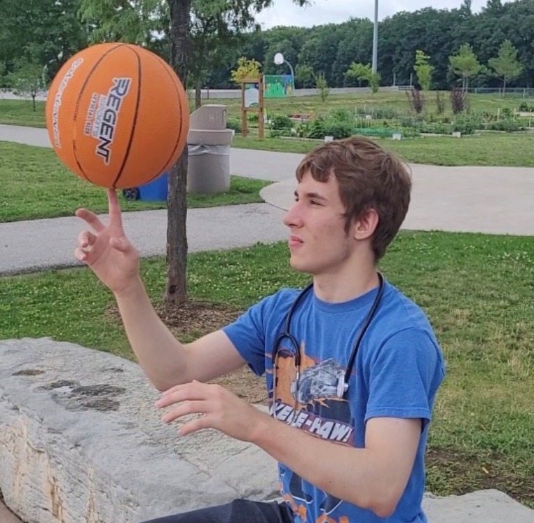 An older boy in a blue shirt balancing a basketball on his finger